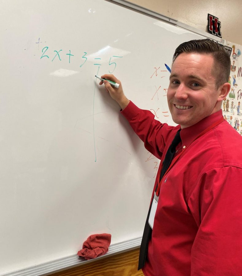 Mr. Cummings solving a math problem on the white board.